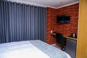 a bedroom with a bed and a desk with a television at Delux Guesthouse in Volksrust