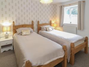 two beds in a bedroom with two lamps and a window at 20 Porth Y Llechen in Y Felinheli