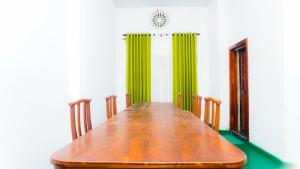 a long wooden table in a room with green curtains at V6 Holiday Bungalow in Badulla