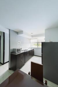 a large kitchen with black cabinets and a large window at Apartamento Eje Cafetero a 2 km Parque del Café in Montenegro