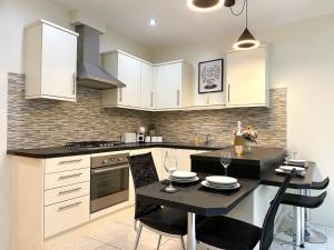 a kitchen with white cabinets and a table with chairs at On Trend 3 Bedroom Home In Maerdy near Attractions 