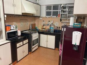 a kitchen with white cabinets and a purple refrigerator at Crimson Apartment in Darjeeling