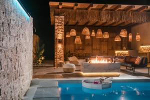 an outdoor living room with a fireplace and a pool at Le Ialyse Luxury Villa in Ialysos