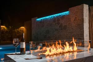 a wine glass and a bottle of wine next to a fireplace at Le Ialyse Luxury Villa in Ialysos