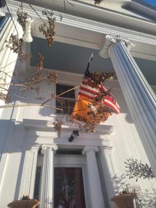 an american flag hanging on the side of a building at House of 1833 Bed and Breakfast in Mystic