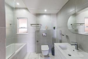 a bathroom with a sink and a toilet and a tub at Santorini - Perissa 41 in Ballito