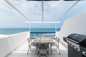 a table and chairs on a balcony with the ocean at Santorini - Perissa 41 in Ballito