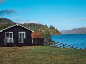 a small house next to a body of water at Cabins at Old Pier House in Fort Augustus
