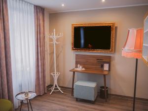 a living room with a tv on the wall and a table at Boutique Hotel Stadtmitte in Mülheim an der Ruhr