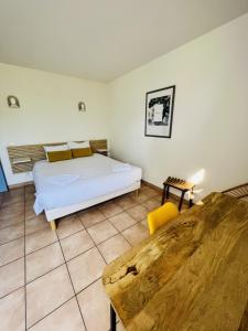 BaixにあるHôtel Rose des Ventsのベッドルーム(白いベッド1台、黄色い椅子付)