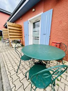 einem grünen Tisch und Stühlen vor einem Gebäude in der Unterkunft Hôtel Rose des Vents in Baix