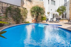 a large blue swimming pool next to a building at Mosta Dome B&B in Mosta