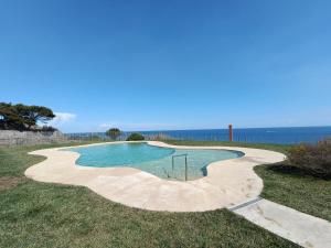 a swimming pool in a field with the ocean in the background at Appartamento incantevole con piscina in Cervo