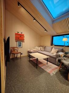 een woonkamer met een bank en een tv bij Huset ved skogen in Isfjorden