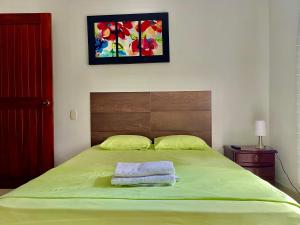 a bedroom with a green bed with two towels on it at Quinta Baroe in Guaduas
