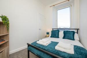um quarto com uma cama com almofadas azuis e uma janela em Brulee House - Luxury 2 Bed Apartment in Aberdeen Centre em Aberdeen
