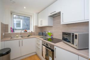 una cocina con armarios blancos y electrodomésticos de acero inoxidable en Brulee House - Luxury 2 Bed Apartment in Aberdeen Centre, en Aberdeen
