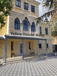 ein gelbes Haus mit einem Schild auf der Vorderseite in der Unterkunft Yellow House Suite in Madschdal Schams