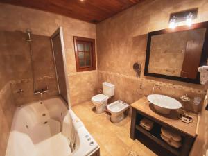 a bathroom with a tub and a sink and a toilet at Boutique Hotel La Cantera in El Calafate