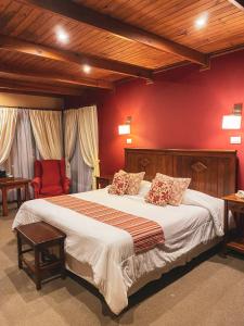 um quarto com uma cama grande e paredes vermelhas em Boutique Hotel La Cantera em El Calafate
