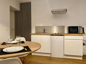 a kitchen with a table and a microwave and a table with wine glasses at Détente & Spa in Villers-Allerand