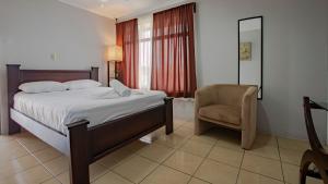 a bedroom with a bed and a chair at Coati Arenal Lodge in Fortuna