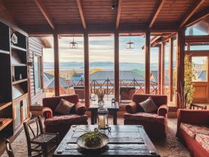 een woonkamer met een tafel, stoelen en ramen bij Boutique Hotel La Cantera in El Calafate