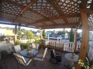 a patio with two tables and chairs under a wooden pergola at Mariana's Petit Hotel in Guatemala