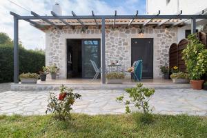 a stone house with a pergola and a patio at villa on the sea in Ayía Marína