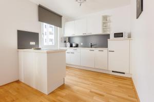 een witte keuken met witte kasten en een houten vloer bij Home in Vienna by Oberlaa Therme - 15 min to the city center in Wenen
