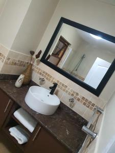uma casa de banho com um lavatório e um espelho em Ocean View Villas Unit H07 em Port Edward