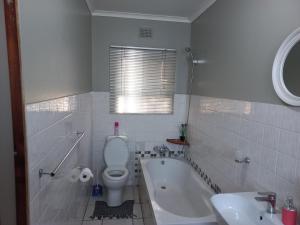 een badkamer met een bad, een toilet en een wastafel bij Elegant 1-Bedroom Apartment with pool. in Richards Bay