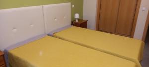 due letti in una stanza con lenzuola gialle di Rocha Apartment a Portimão