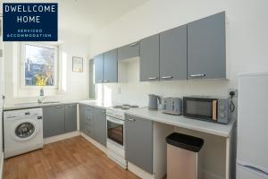 a kitchen with gray cabinets and a sink and a microwave at Dwellcome Home Ltd 3 Double Bedroom Aberdeen Apartment - see our site for assurance in Aberdeen