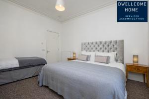 a white bedroom with a large bed and two lamps at Dwellcome Home Ltd 3 Double Bedroom Aberdeen Apartment - see our site for assurance in Aberdeen