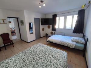 um quarto com 2 camas, uma televisão e uma cadeira em Maison individuelle 60 m² em Le Cateau
