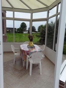 una mesa con sillas y un jarrón en un porche en Chez DOUDOU entre terre et mer, en Bretteville-Saint-Laurent