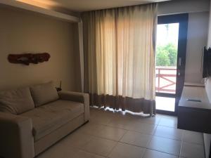 - un salon avec un canapé et une grande fenêtre dans l'établissement Kariri Beach - Apartamento Superior, à Cumbuco