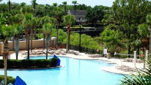a large swimming pool with palm trees and chairs at Windsor Hills Resort- 205 in Orlando