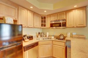 a kitchen with wooden cabinets and a stainless steel refrigerator at Villas of Hatteras Landing by KEES Vacations in Hatteras
