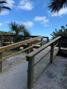 un puente de madera en la playa con una palmera en Richard Arms Unit 12 en Cocoa Beach