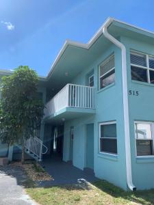 a blue building with a balcony and a tree at Richard Arms Unit 12 in Cocoa Beach