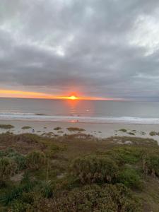 una puesta de sol sobre una playa con el océano en Richard Arms Unit 12 en Cocoa Beach