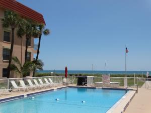 a swimming pool with chairs and the ocean in the background at Spanish Main Unit 4- Direct Oceanfront Condo! in Cocoa Beach