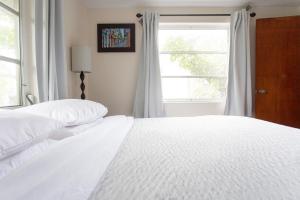1 dormitorio con 2 camas blancas y ventana en Cozy 1 Bedroom Unit - 4 Blocks from Jax Beach Pier! en Jacksonville Beach