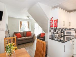 een keuken en een woonkamer met een bank en een tafel bij Jasmine Cottage in Windermere