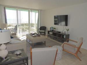 a living room with a couch and a tv at Renovated, Ocean Beach Villas Unit 201- Direct Oceanfront Condo! in Cocoa Beach