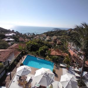 uma vista para uma piscina com guarda-sóis e para o oceano em Pousada Vila do Sol em Búzios