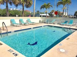 - une piscine avec des chaises bleues dans un complexe dans l'établissement Ocean Beach Villas Unit 203- Direct Oceanfront Condo!, à Cocoa Beach