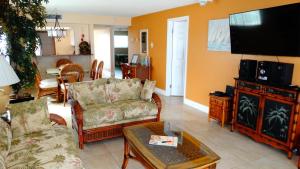 a living room with a couch and a tv at Ocean Beach Villas Unit 203- Direct Oceanfront Condo! in Cocoa Beach